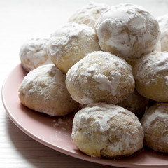 Homemade white mexican wedding cookies on pink plate, side view. Close-up.