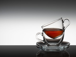 The tea set consists of two glass bowls and a saucer on a gray background.