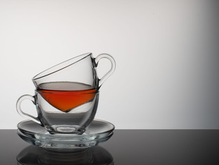 The tea set consists of two glass bowls and a saucer on a gray background.