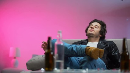 Happy drunk guy chilling out on couch at party, confetti falling down, relax