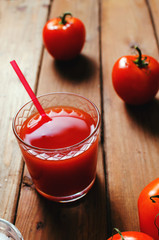 Tomato juice in glass with fresh tomatoes and salt. Rustic wooden background.