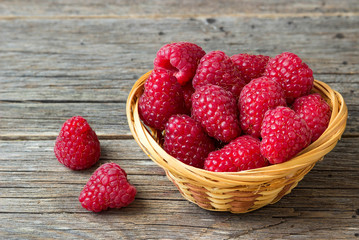 Raspberries  in a basket on a wooden table.
