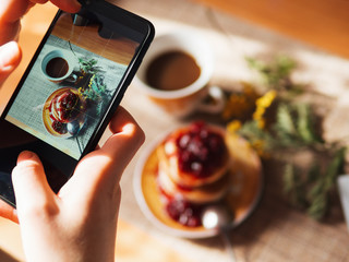 Women's hands take pictures of Japanese pancakes with jam