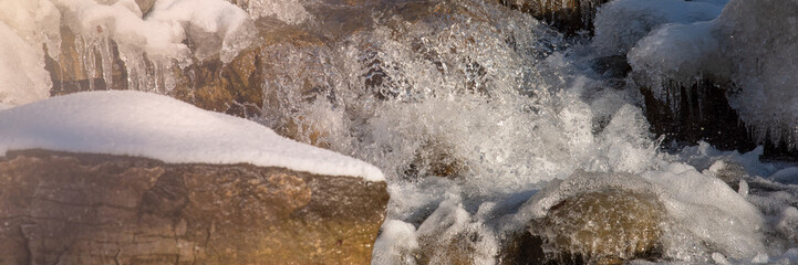 Water flowing in rapids over stone, in the winter mountains