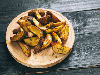 Country potato crispy on a dark wooden table . Fast food French fries