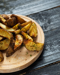Country potato crispy on a dark wooden table . Fast food French fries