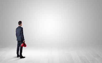 Fototapeta premium Man standing with his back in an empty room with object in his hand