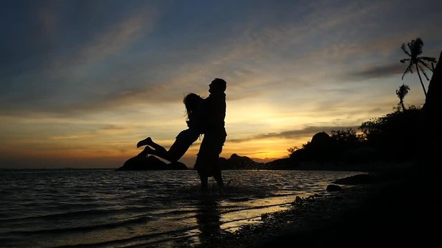 Silhouette of romantic young couple spinning around at amazing sunset, slow motion. 1920x1080