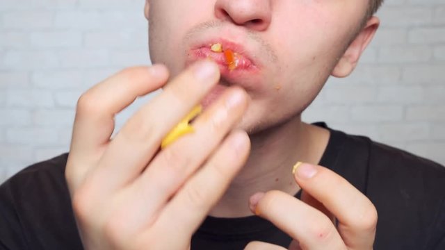 young man eats a juicy cheeseburger and licks his fingers. pleasure of eating.