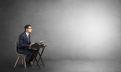 Man working hard on a typewriter in an empty space
