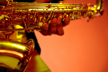 African American handsome jazz musician playing the saxophone in the studio on a neon background....