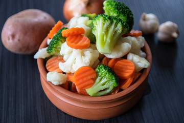 Fresh organic vegetables in a ceramic bowl: cauliflower, Broccoli, carrot, potato, onion and garlic