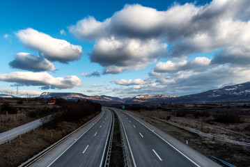 Fototapeta premium Empty freeway or motorway with mountains in the background and with beautiful dramatic sky