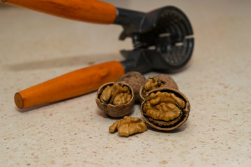 cracked wallnuts with nut cracker in the background