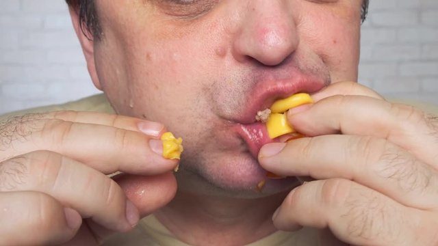 hungry man eats a juicy cheeseburger and licks his fingers. pleasure of eating.