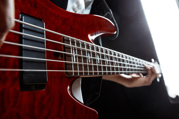 Fototapeta premium African American handsome jazz musician playing bass guitar in the studio on a black background. Music concept. Young joyful attractive guy improvising. Close-up retro portrait.
