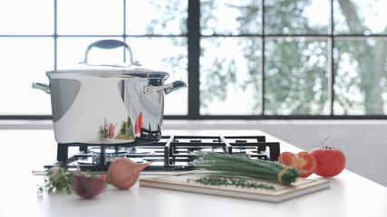 The new chrome pan on the mirror cooking plate in the white interior. Fresh vegetables lie near a...