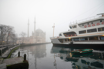 Fototapeta premium Foggy day, Ortaköy Mosque and Passenger Ferry in Istanbul, Turkey.
