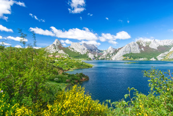 Fototapeta na wymiar montañas calizas de Picos de Europa sobre el pantano de Riaño en primavera con los bosques verde y el cielo azul