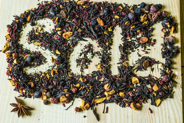 The inscription "Sold" on herbal tea with a cup of red tea on a light wooden background