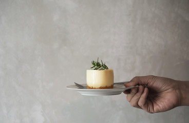 Hand holding beverage dessert over tray cement wall background with copy space - coffee break time concept