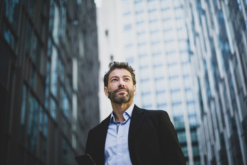 Businessman walking in city using smartphone