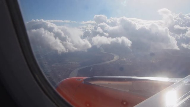 Airplane window view slow motion. Sunny day with clouds.