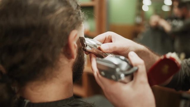 the Barber trims the beard of a bearded man