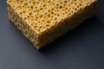Close up view of cleaning sponge, mesh structure pattern on black surface. Yellow sponge close-up shot.
