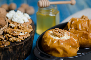 healthy food. Baked apples with cottage cheese and nuts lie in a black baking dish on a blue wooden table