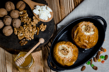 healthy food. Baked apples with cottage cheese and nuts lie in a black baking dish on a wooden table