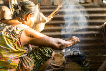 Rural people are cooking food with firewood, dried wood, with smoke.