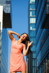 Young beautiful girl posing against the blue sky and high-rise buildings