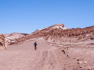 Cyclist on a lonely dust road in Valle de la Luna, San Pedro de Atacama, Chile