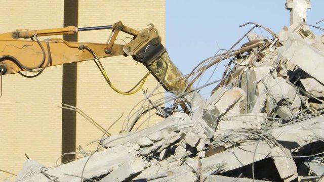 Tractor with manipulator rakes the ruins on the construction site
