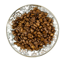 Brown coffee beans on plate with oriental pattern. Top view flat lay. Isolated on white background.