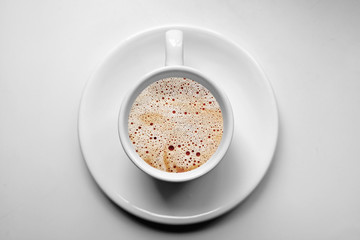 Coffee cup on white saucer, isolated on white table background - top view of breakfast drink