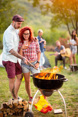 Curly ginger girl with tattooed guy look at grill fire