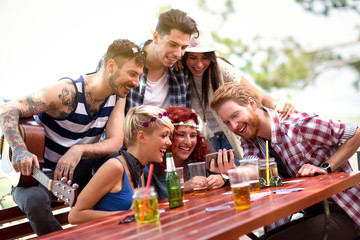 Young team are laughing while watching their photos on mobile phone
