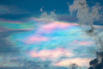 Colorful iridescent sky with dark clouds in the evening time.  