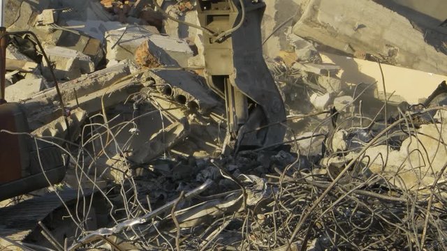 Tractor rakes pieces of the building in the ruins of the construction site