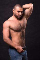 Brutal muscular man, in jeans. Tioless bodybuilder posing standing.