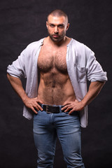 Fototapeta na wymiar Brutal muscular man, in jeans and cotton shirt. Bodybuilder relaxing standing.