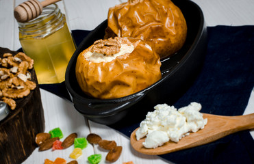 healthy food. Baked apples with cottage cheese and nuts lie in a black baking dish on a white wooden table