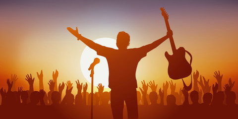 Concept du concert de musique rock avec un chanteur qui salue son public en brandissant sa guitare et la foule qui l’applaudit à la fin du spectacle. - obrazy, fototapety, plakaty