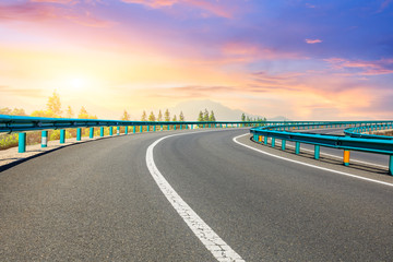 Fototapeta premium Asphalt highway and forest with mountain scenery at sunset