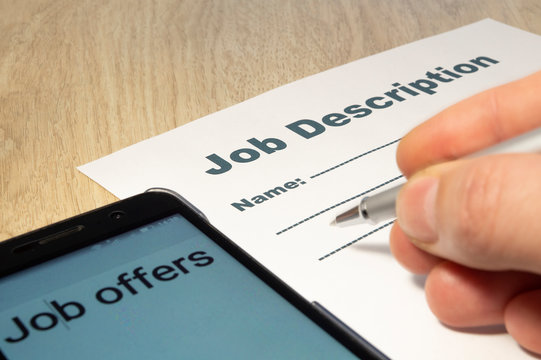 Job Description with Hand, smartphone and Pen on the table.