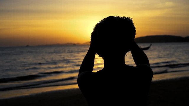 Silhouette back of young male travel backpacker with hat taking photos of summer beach scenery against sunset - travel picture moment captured concept.