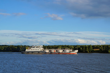 Fototapeta premium Cargo ship goes along the Volga river, Russia. Bright sunny summer evening