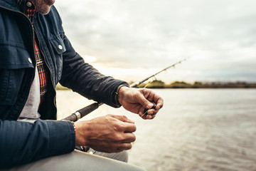 Close up of a man sitting near a lake to do fishing